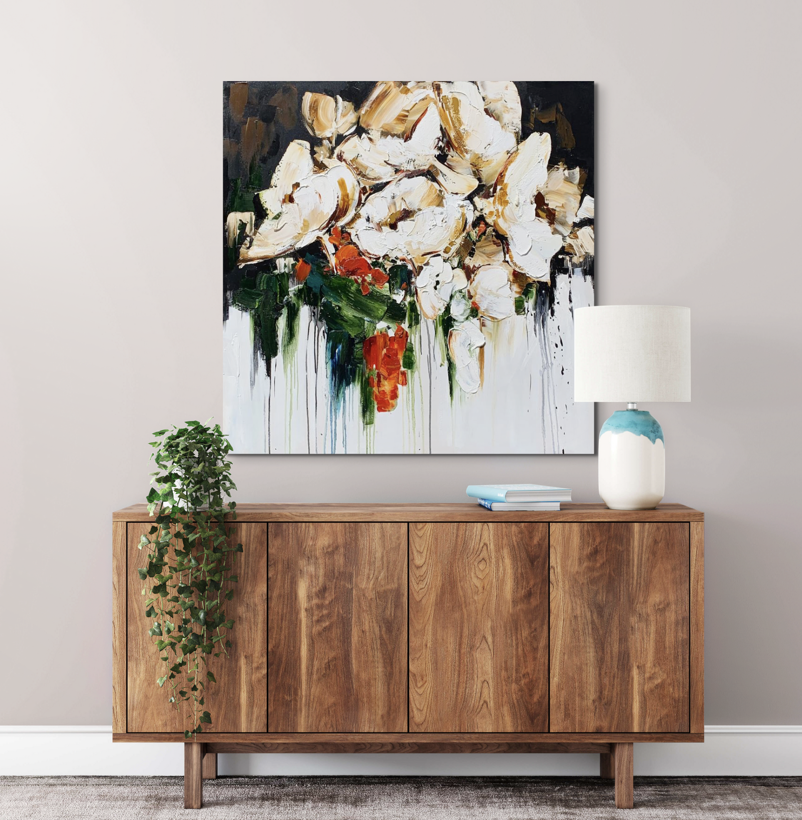 Kimberly Kiel oil painting of white and orange flowers with green leaves dripping own a white canvas above a wooden mid-century modern cabinet.
