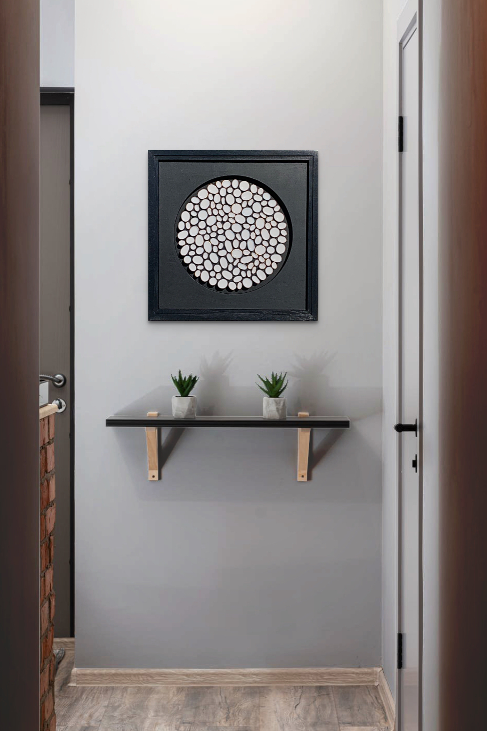 Black, copper, and white abstract painting by Richelle Osborne on a soft warm grey wall above a small shelf with two small succulent plants.